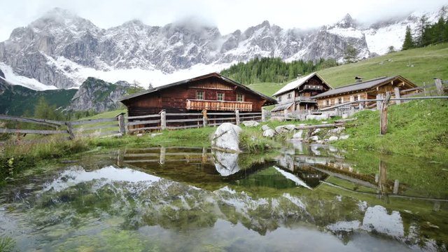 	Alpine mountain scenery with traditional farmhouses reflecting in lake