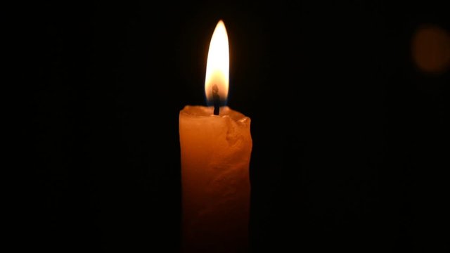 Burning candle on a dark background in slow motion.