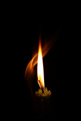 One light candle burning brightly in the black background.