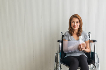 Fototapeta na wymiar Broken arm Asian woman with arm sling sponsored in her hands sitting on a wheelchair Ideas for accident Injuries and health care Studio shot on a white background.