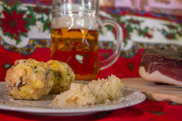 two knodels on the plate with sauerkraut and speck on the background and mug of beer and Christmas tablecloth