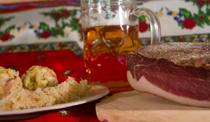 two knodels on the plate with sauerkraut and speck on the background and mug of beer and Christmas tablecloth
