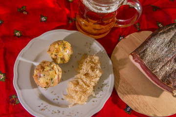 two knodels on the plate with sauerkraut and speck on the background and mug of beer and Christmas tablecloth