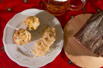 two knodels on the plate with sauerkraut and speck on the background and mug of beer and Christmas tablecloth