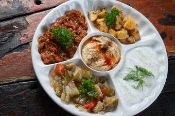 Mix plate Arabic food with vegetarian spread starters isolated on rustic wooden background