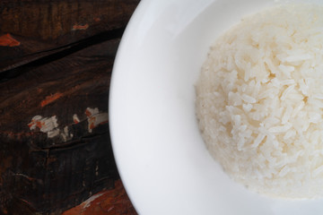 Closeup top view of Jasmine rice on the white plate isolated on rustic wooden kitchen table