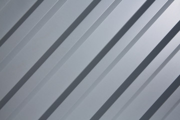 Obraz premium there is a galvanized ribbed painted gray metal profile for fences, roofs, walls. Front view of gray ribbed metal surface on fence or wall for background. gradient light, diagonal arrangement.