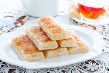 Baking tongues from puff pastry with sugar on a white plate, selective focus