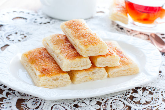 Baking tongues from puff pastry with sugar on a white plate, selective focus