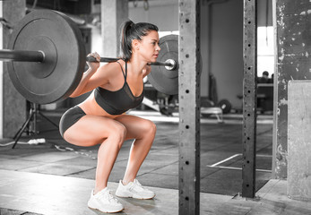 Obraz na płótnie Canvas Side view of a woman in the gym. Hard training. Squat.