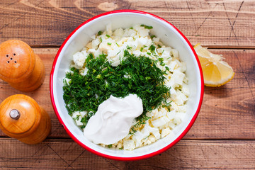 Step by step cooking of egg salad with leek and dill, step 4 adding sour cream, lemon juice, spices, selective focus, top view