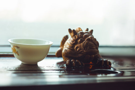 Chinese tea ceremony on a table with decorative figurine of a dragon.
