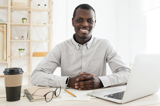 Portrait of handsome african american black young business man working on laptop at office desk