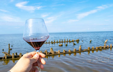 A glass of red wine on the sandy beach in summer.