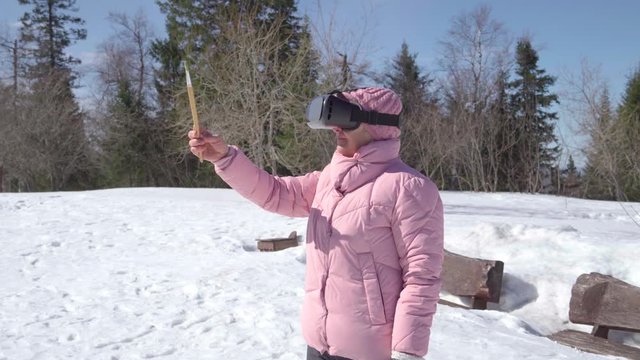 Grandma in virtual glasses is going to paint a picture. Woman in winter outdoors prepare to draw.