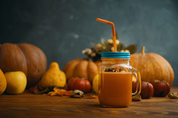 Pumpkins juice in bottles with pumpkins. Glass of fresh pumpkin smoothie on wooden background