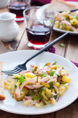 traditional german potato salad with sausage and pickled cucumbers, selective focus