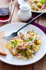 traditional german potato salad with sausage and pickled cucumbers, selective focus