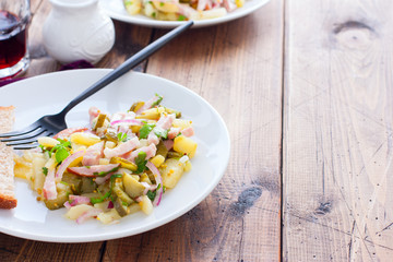 traditional german potato salad with sausage and pickled cucumbers, horizontal, copy space