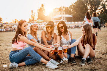 Female friends cheering with beer at music festival