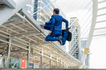 motion blurred of Asian businessman in formal wear holding briefcase while running and jump in the city on a background of building. late for work concept