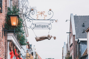 The signboard of an antique dealer decorated with an angel of straw during the Dickens Festival