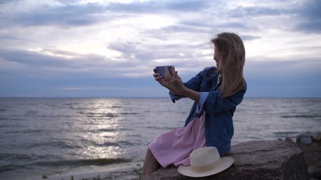 A young woman joyfully takes a selfie by the ocean. 4K Slow Mo