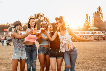 Female friends cheering with beer at music festival