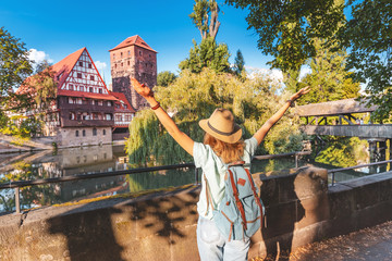 Happy asian woman tourist enjoying sunset view of the old town of Nurnberg city and Pegnitz river....