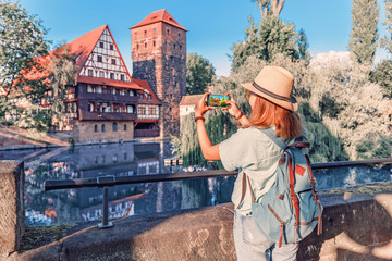 Happy asian woman tourist taking photo of the old town of Nurnberg city and Pegnitz river. Travel...
