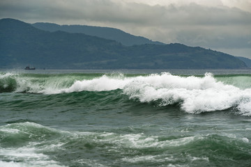 Stormy sea view near coastline at evening. Waves and splashed drops