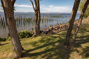 View of Columbia River from City of Astoria Maritime Museum, Oregon, USA. Waterfront river view with wooden pylons, boats in distance.