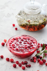 Cranberry jam in a glass bowl and teapot on a white background.
