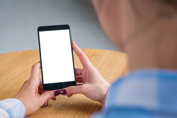 Mockup image: woman looking at black smartphone with white blank screen. Close up view of woman hands with smart phone mobile device. Mock up, copyspace, template and technology concept