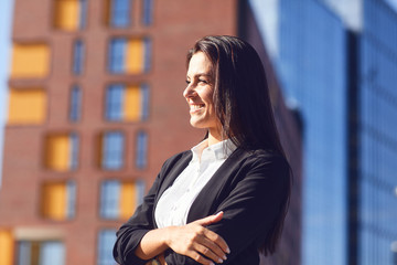 A happy businesswoman is smiling outdoors.