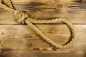 Obraz premium Deadly loop of rope on a wooden background. Concept of death penalty or suicide