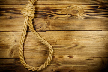 Obraz premium Deadly loop of rope on a wooden background. Concept of death penalty or suicide