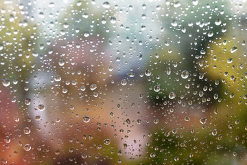 Raindrops on a window pane. Colorful autumn abstract background in soft colors.