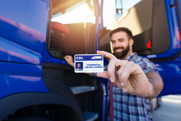 Portrait of middle aged bearded truck driver standing by his truck and showing his commercial...