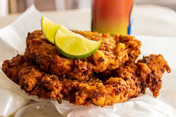 Two delicious conch fritters with sliced limes served as an appetizer.