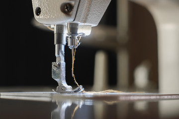 Close-up needle of white industrial sewing machine use sew cloth.