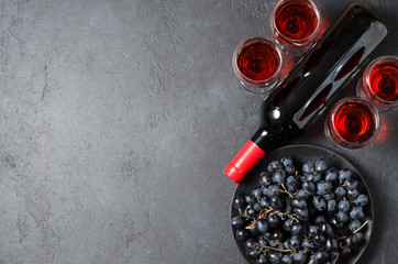 Red wine in glasses, a bottle of wine, black grapes. Dark background. Copy space.
