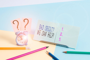 Writing note showing Bad Creditquestion We Can Help. Business concept for offerr help to gain positive payment history Mini size alarm clock beside stationary on pastel backdrop