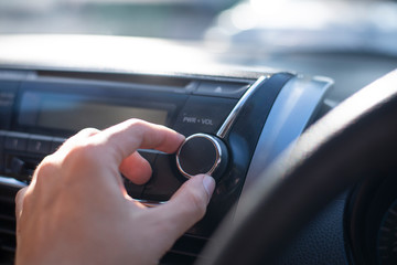 People hand is control sound volume of radio in the car while listening to music.