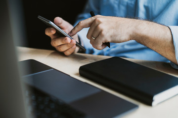 Man sitting at desk, texting on smartphone.Office worker socializing on mobile phone.Close-up male hands typing on cellphone.