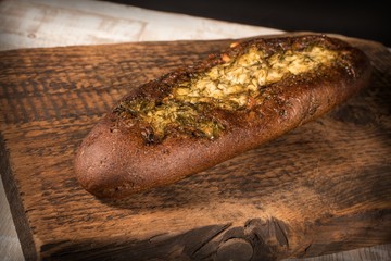 Rye baguette with garlic sauce and dill on a dark textured wooden surface