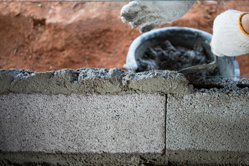 Bricklayer putting down another row of bricks in site