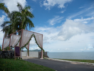 Wedding arch cover by white cloth and green leaves at beautiful beach with blue sky and nice weather.