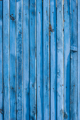 Fence made of narrow old blue planks. Boards with knots and slots are arranged vertically. Vertical frame.