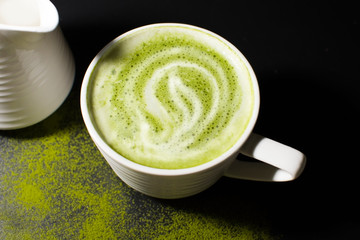 Hot matcha green tea a bowl with milk foam late art on wood table background